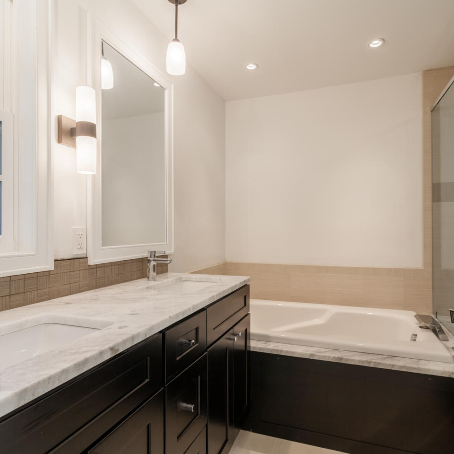 Tub deck extends into shower for seating. Waterfall tub filler. Custom mirror to match window frame.
